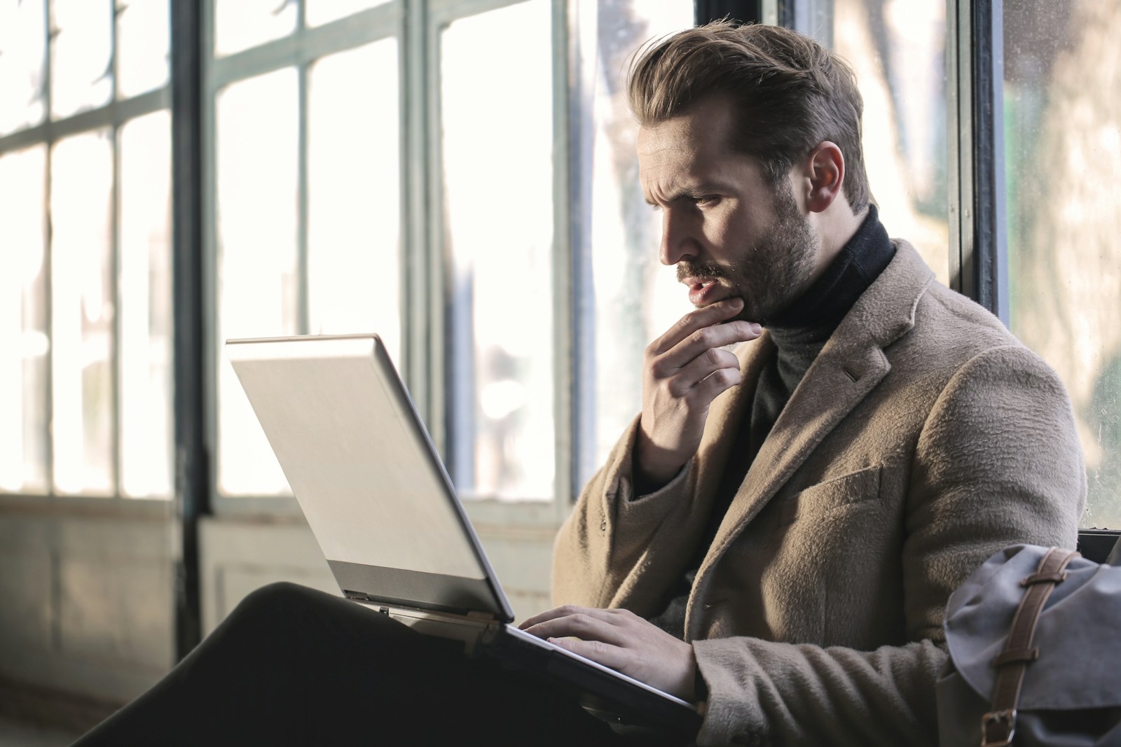 man holding his chin facing laptop computer, executive coaching for Men in san Diego